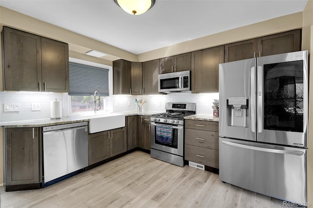 1348 Tull Dr, Waterford, MI 48327 - kitchen featuring stainless steel appliances, light countertops, dark brown cabinets, light wood-style flooring, and tasteful backsplash