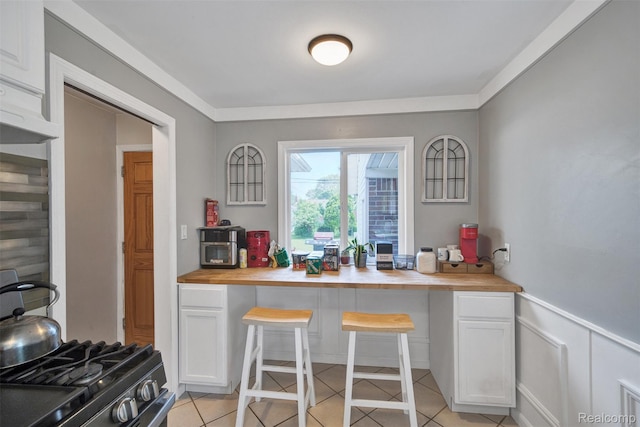 11214 Canal Rd, Sterling Heights, MI 48314 - kitchen with butcher block countertops, white cabinetry, gas stove, and light tile patterned flooring
