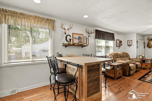 4162 9th St, Newport, MI 48166 - kitchen with wood finished floors, a textured ceiling, a kitchen bar, and recessed lighting