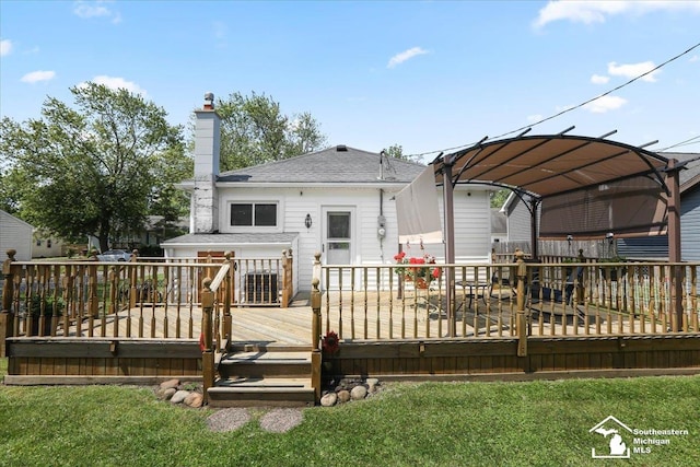 4162 9th St, Newport, MI 48166 - rear view of house featuring a wooden deck, a chimney, roof with shingles, and a lawn