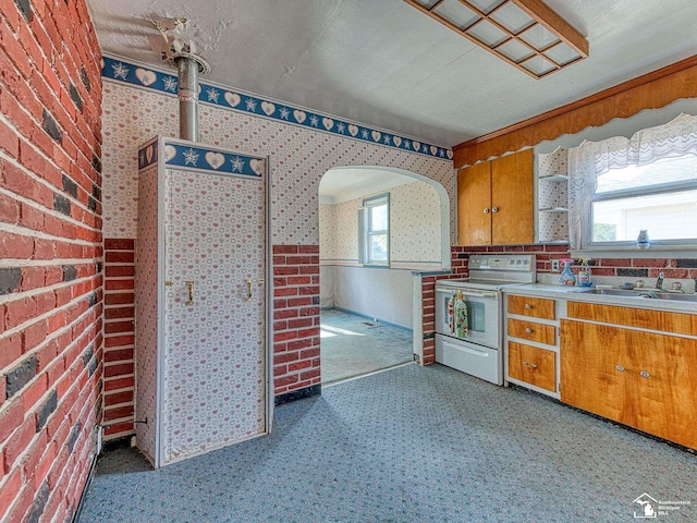 2109 Spaulding Rd, Monroe, MI 48162 - kitchen featuring electric stove, brown cabinetry, light countertops, wallpapered walls, and arched walkways