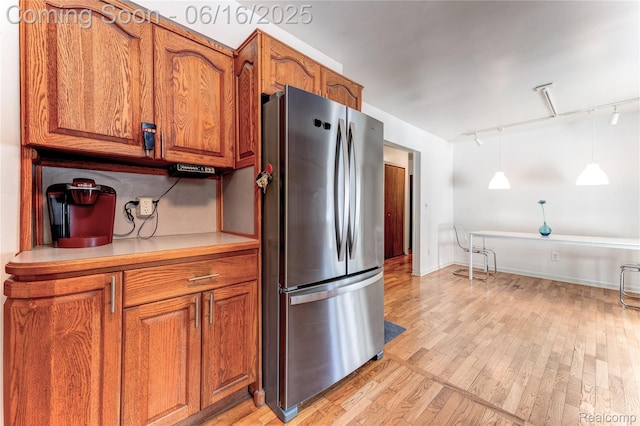 11704 Schram St, Grand Blanc, MI 48439 - kitchen featuring freestanding refrigerator, track lighting, brown cabinetry, light wood-type flooring, and hanging light fixtures