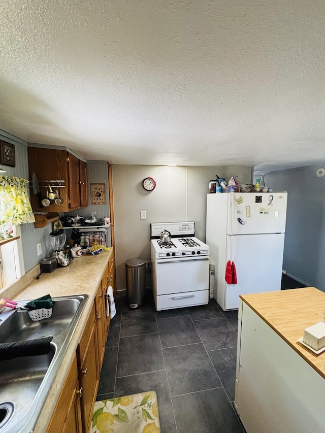 21794 30th Ave, Barryton, MI 49305 - kitchen with white appliances, brown cabinets, light countertops, a textured ceiling, and dark tile patterned floors