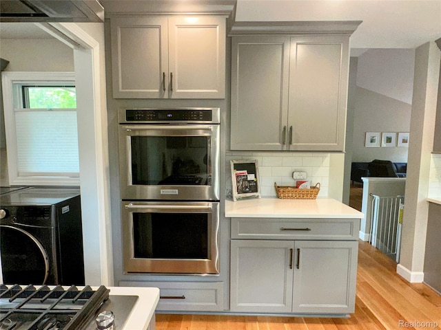6771 Foxboro, Brighton, MI 48116 - kitchen with stainless steel double oven, gray cabinetry, backsplash, light wood finished floors, and light countertops