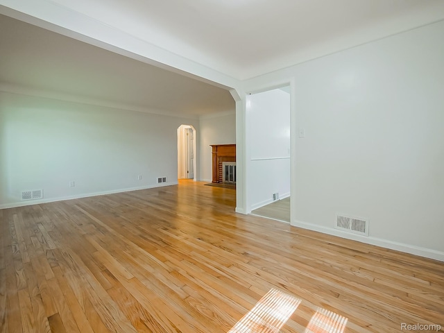 23740 Lee Baker Dr, Southfield, MI 48075 - empty room with arched walkways, light wood finished floors, and a brick fireplace