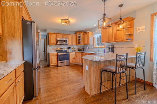 15980 Monterey St, Southgate, MI 48195 - kitchen featuring appliances with stainless steel finishes, a peninsula, backsplash, light wood finished floors, and a kitchen breakfast bar