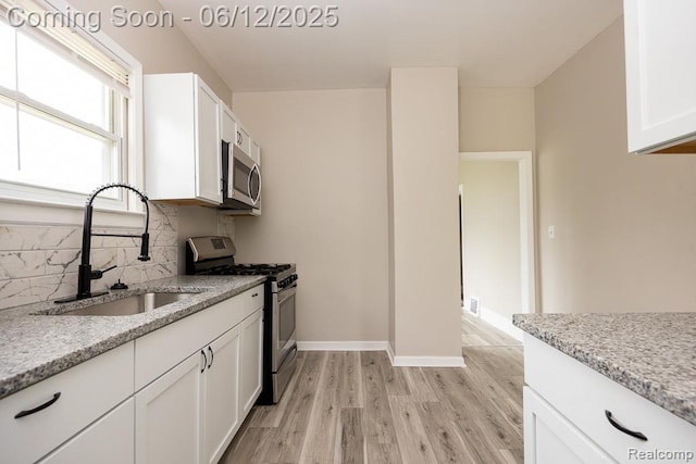 15834 Baylis St, Detroit, MI 48238 - kitchen featuring appliances with stainless steel finishes, light wood-type flooring, white cabinets, tasteful backsplash, and light stone counters