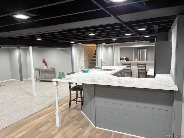 2211 Parkside St, Trenton, MI 48183 - kitchen featuring light wood-style floors, light countertops, a breakfast bar area, and freestanding refrigerator