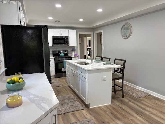 2211 Parkside St, Trenton, MI 48183 - kitchen with appliances with stainless steel finishes, a breakfast bar area, light countertops, light wood-style flooring, and recessed lighting