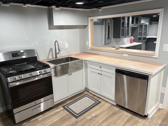 2211 Parkside St, Trenton, MI 48183 - kitchen featuring appliances with stainless steel finishes, butcher block counters, light wood-style floors, and white cabinetry