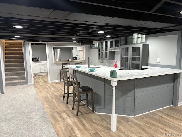 2211 Parkside St, Trenton, MI 48183 - kitchen with a peninsula, a kitchen breakfast bar, glass insert cabinets, stainless steel microwave, and light wood-style floors