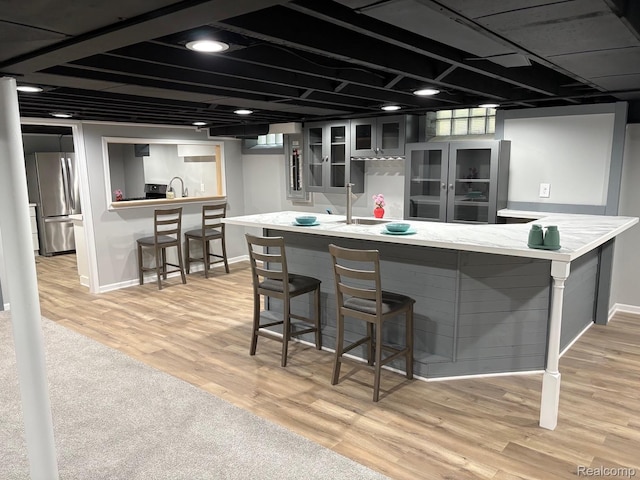 2211 Parkside St, Trenton, MI 48183 - kitchen featuring freestanding refrigerator, light wood-type flooring, glass insert cabinets, and a breakfast bar area