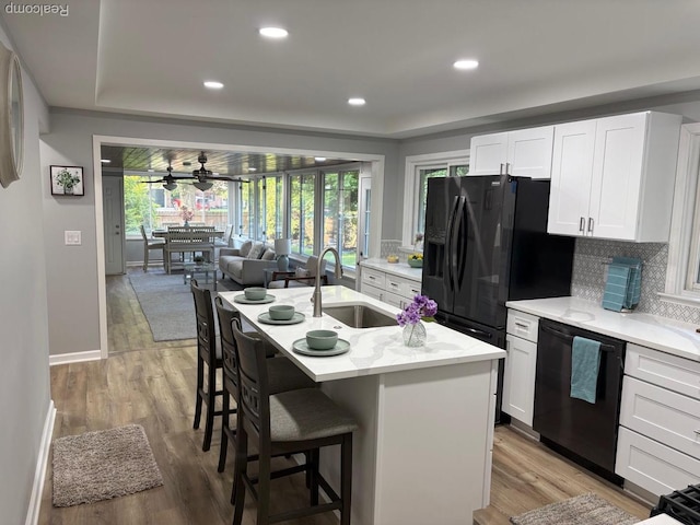 2211 Parkside St, Trenton, MI 48183 - kitchen with black appliances, white cabinetry, a breakfast bar area, open floor plan, and tasteful backsplash