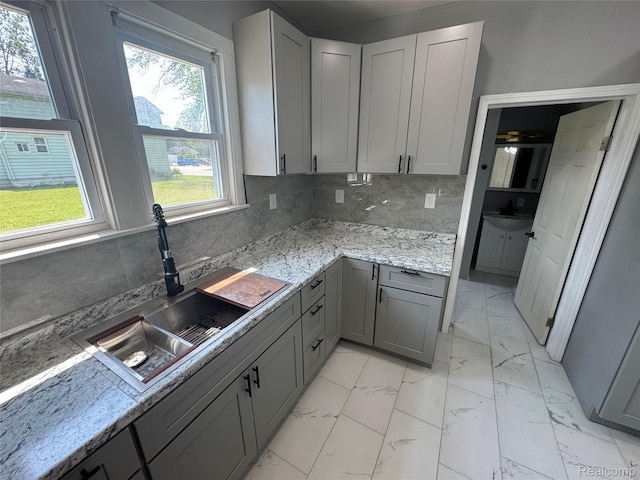 1112 Brockway Rd, Saginaw, MI 48602 - kitchen with gray cabinetry, light marble finish flooring, decorative backsplash, and light stone counters