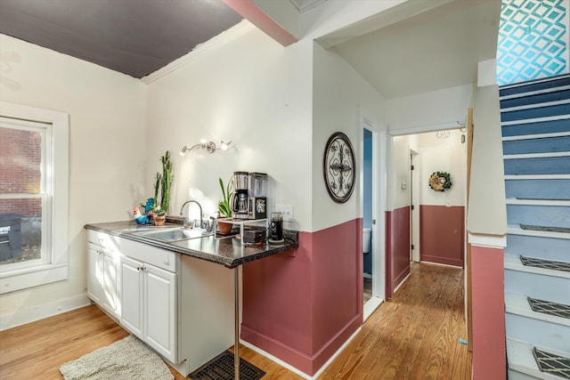 626 Hiscock St, Ann Arbor, MI 48103 - kitchen with light wood-type flooring, white cabinets, ornamental molding, and dark countertops