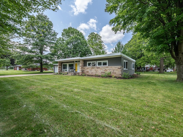 219 Park St, Tecumseh, MI 49286 - view of front of property with stone siding, a front lawn, and a garage