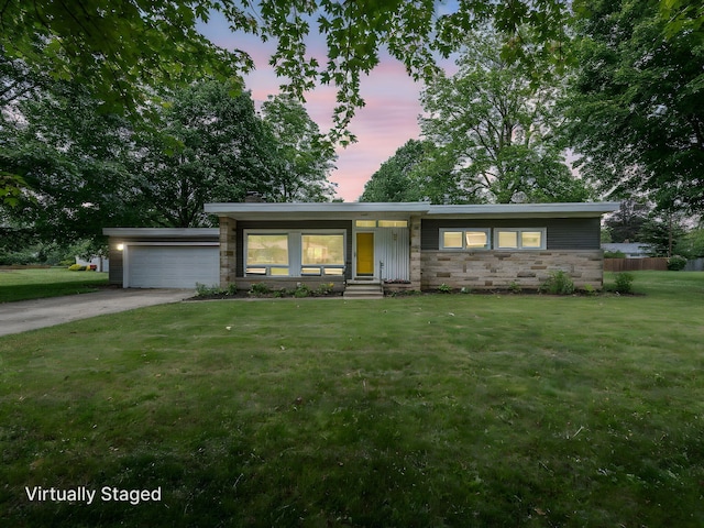 219 Park St, Tecumseh, MI 49286 - mid-century modern home featuring stone siding, a front yard, a garage, driveway, and entry steps