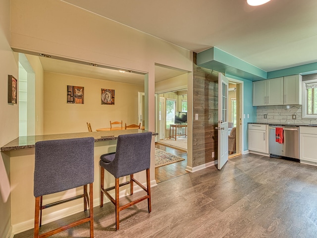 219 Park St, Tecumseh, MI 49286 - kitchen featuring stainless steel dishwasher, wood finished floors, a breakfast bar, and dark stone countertops