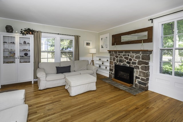 3444 Broad St, Dexter, MI 48130 - living room featuring healthy amount of natural light, wood finished floors, a stone fireplace, a wainscoted wall, and crown molding