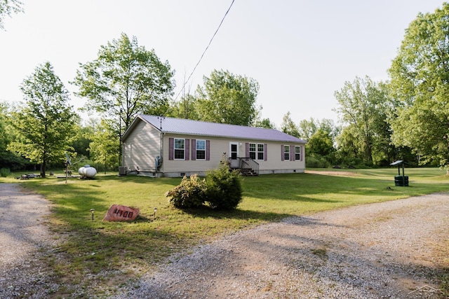 4100 Maloney Rd, Pinconning, MI 48650 - view of front facade featuring driveway, a front lawn, crawl space, and a metal roof