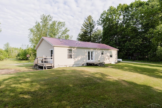 4100 Maloney Rd, Pinconning, MI 48650 - rear view of property featuring a deck, a lawn, a metal roof, and crawl space
