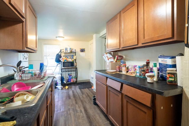635 Sinclair Ave NE, Grand Rapids, MI 49503 - kitchen featuring stainless steel microwave, dark wood-style floors, dark countertops, and brown cabinets