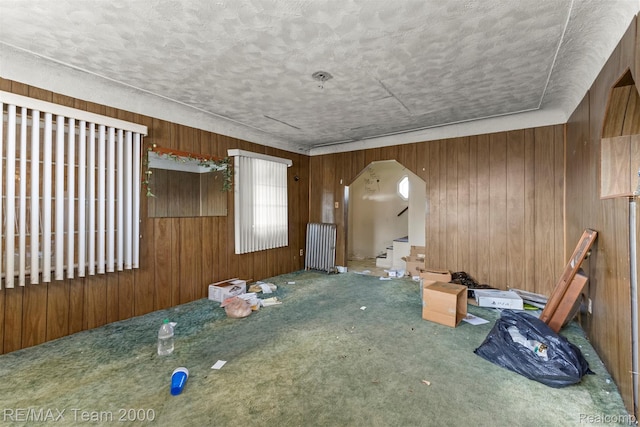3966 12th St, Ecorse, MI 48229 - empty room featuring wooden walls, carpet floors, a textured ceiling, arched walkways, and stairway