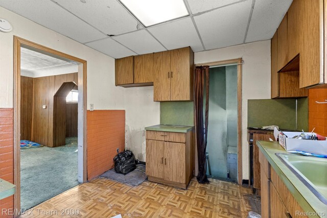3966 12th St, Ecorse, MI 48229 - kitchen featuring brown cabinets, light countertops, a paneled ceiling, and wooden walls