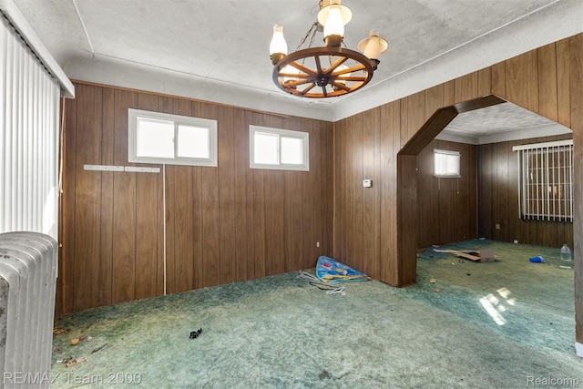 3966 12th St, Ecorse, MI 48229 - carpeted empty room with radiator, a chandelier, and wood walls
