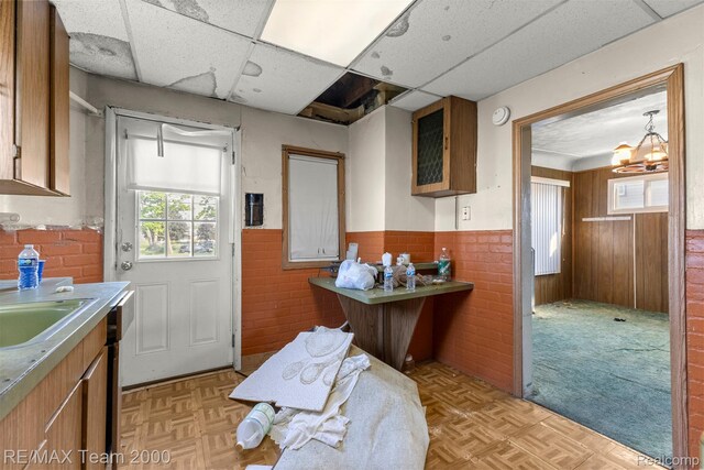 3966 12th St, Ecorse, MI 48229 - kitchen with wainscoting, a paneled ceiling, brown cabinetry, and light countertops
