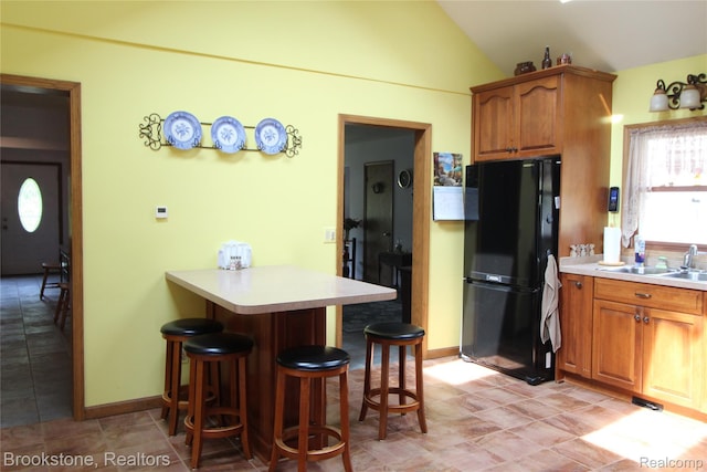 32599 Armada Ridge Rd, Richmond, MI 48062 - kitchen with freestanding refrigerator, a breakfast bar area, a peninsula, lofted ceiling, and light countertops