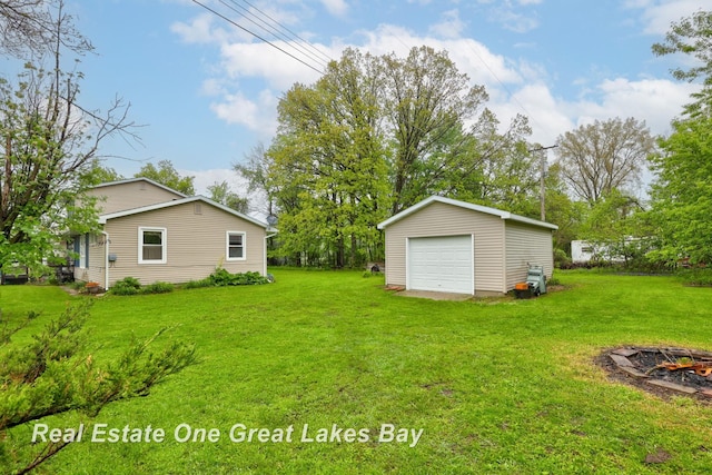 959 N Cass Ave, Vassar, MI 48768 - view of green lawn featuring a detached garage, an outdoor structure, and an outdoor fire pit