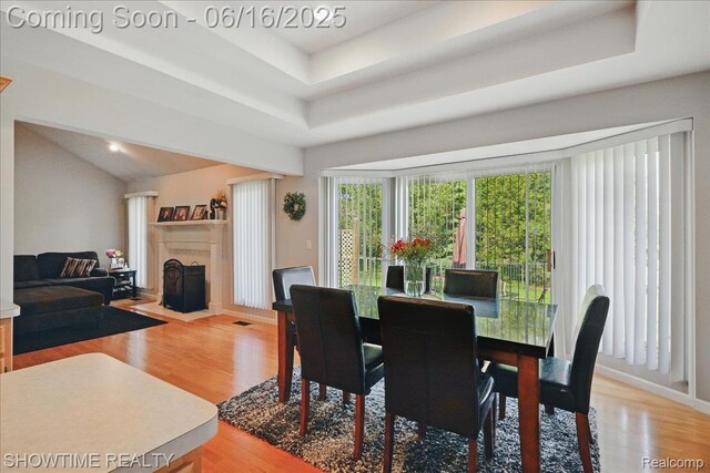 50064 Josephine Dr, Macomb, MI 48044 - dining area with light wood-style floors, a tray ceiling, and a fireplace with flush hearth