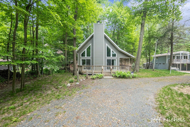 534 N Lighthouse Dr, Mears, MI 49436 - view of front facade with a chimney, a deck, driveway, and view of scattered trees
