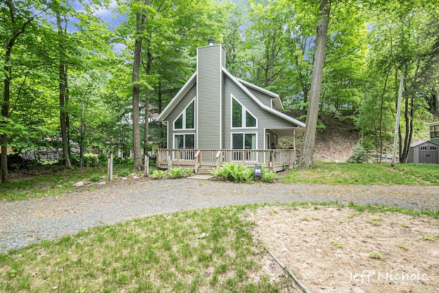 534 N Lighthouse Dr, Mears, MI 49436 - view of front of home with a chimney, a storage unit, a deck, and view of wooded area