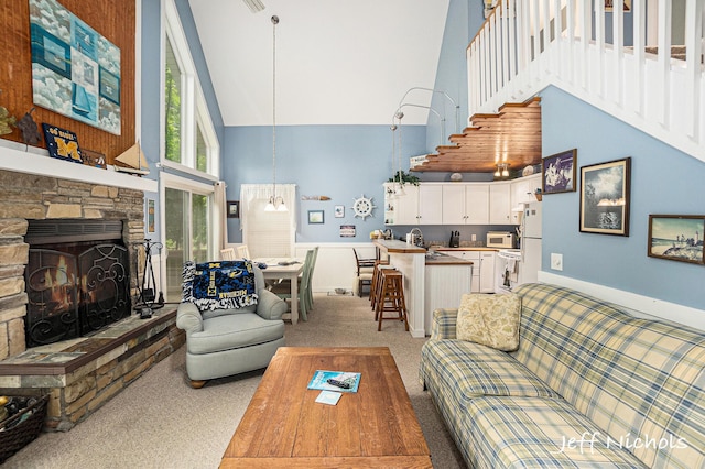 534 N Lighthouse Dr, Mears, MI 49436 - living room with high vaulted ceiling, light carpet, stairway, and a fireplace