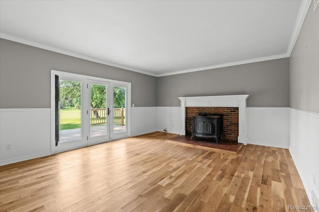3757 Chase Lake Rd, Howell, MI 48855 - unfurnished living room with a wood stove, light wood-style floors, crown molding, and a wainscoted wall