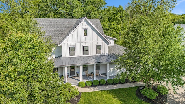 2377 Lake Birch Ct NE, Grand Rapids, MI 49525 - view of front of house featuring board and batten siding, roof with shingles, covered porch, a front lawn, and a standing seam roof