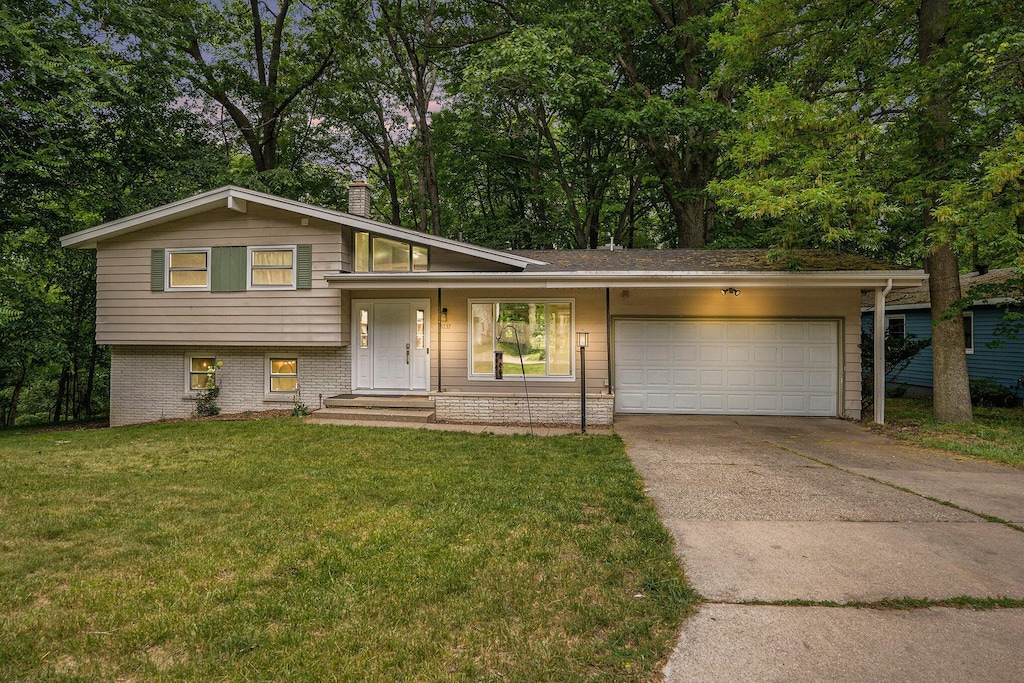 2037 Holliday Dr SW, Wyoming, MI 49519 - tri-level home featuring an attached garage, concrete driveway, and a front lawn