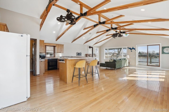 3806 Island Park Dr, Waterford, MI 48329 - kitchen with freestanding refrigerator, open floor plan, black range oven, a kitchen bar, and light countertops
