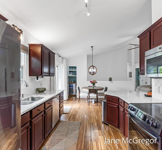 15159 Westray St, Grand Haven, MI 49417 - kitchen featuring stainless steel appliances, wood finished floors, lofted ceiling, a chandelier, and light stone countertops