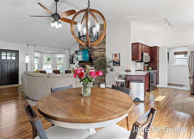 15159 Westray St, Grand Haven, MI 49417 - dining space featuring light wood finished floors, high vaulted ceiling, a chandelier, rail lighting, and a ceiling fan