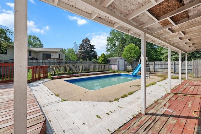 2144 Stanford Dr SE, Kentwood, MI 49508 - view of swimming pool with a storage unit, a fenced backyard, a deck, and a water slide