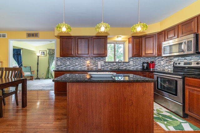 5992 Cedar Ridge Dr, Ann Arbor, MI 48103 - kitchen with appliances with stainless steel finishes, a kitchen island, tasteful backsplash, and wood finished floors