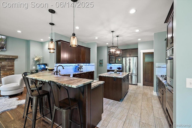5432 Blood Rd, Metamora, MI 48455 - kitchen with appliances with stainless steel finishes, dark brown cabinetry, decorative backsplash, a peninsula, and recessed lighting