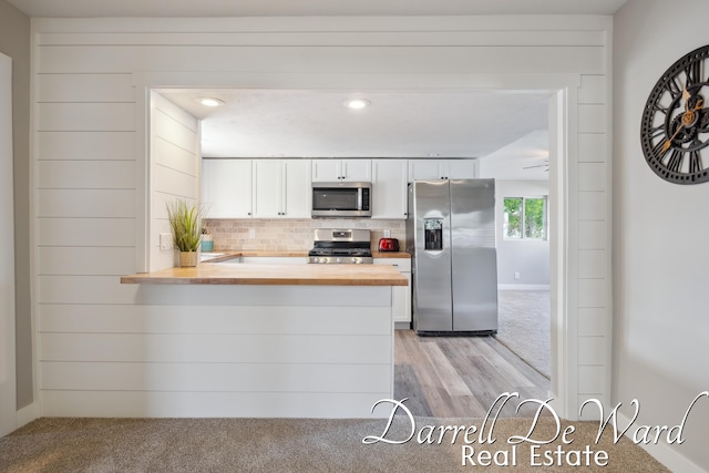 612 E Green St, Hastings, MI 49058 - kitchen with stainless steel appliances, wood counters, white cabinetry, a peninsula, and decorative backsplash