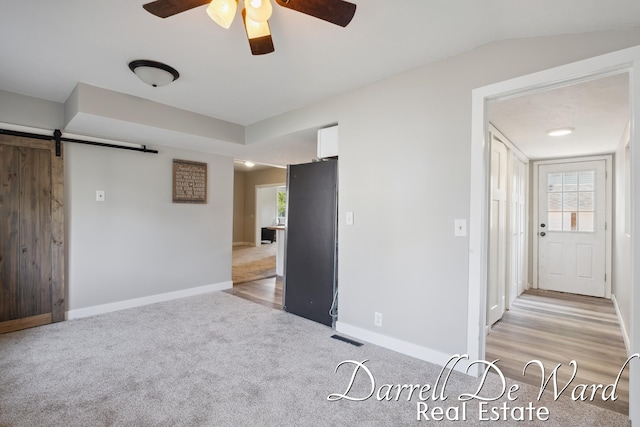 612 E Green St, Hastings, MI 49058 - unfurnished bedroom featuring light colored carpet, multiple windows, a barn door, and a ceiling fan