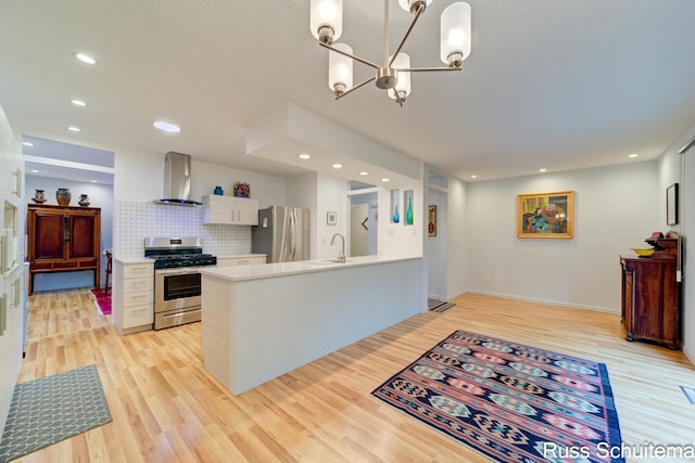1366 W Norton Ave, Muskegon, MI 49441 - kitchen featuring appliances with stainless steel finishes, wall chimney range hood, light wood finished floors, light countertops, and a chandelier