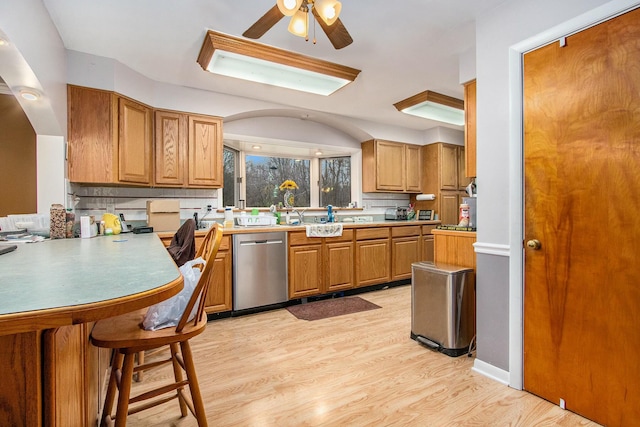 8887 Elm Valley Rd, Union Pier, MI 49129 - kitchen with dishwasher, ceiling fan, light wood-type flooring, a kitchen breakfast bar, and brown cabinetry