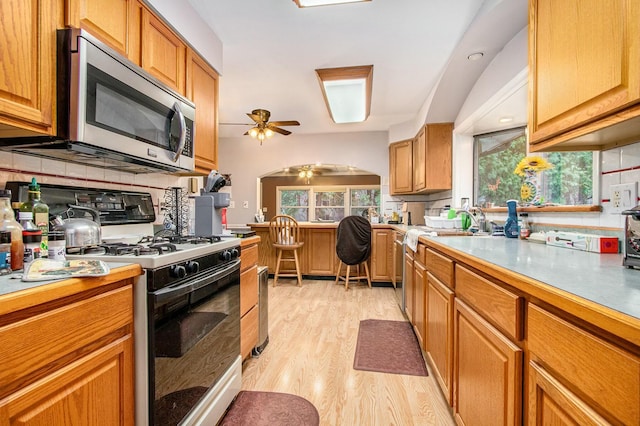 8887 Elm Valley Rd, Union Pier, MI 49129 - kitchen with stainless steel microwave, range with gas cooktop, light wood-type flooring, ceiling fan, and tasteful backsplash